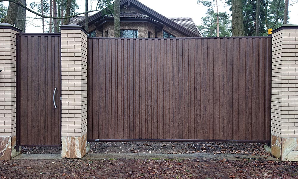Откатные ворота, зашитые проф.листом с имитацией деревянной поверхности. Отдельно стоящая калитка с электромеханическим замком